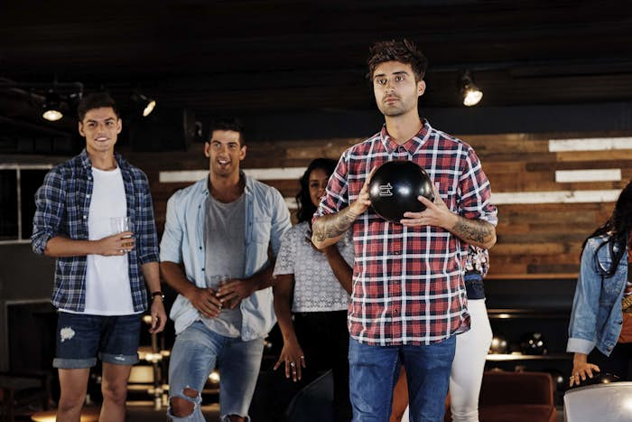 Man preparing to bowl with group of friends watching in the background