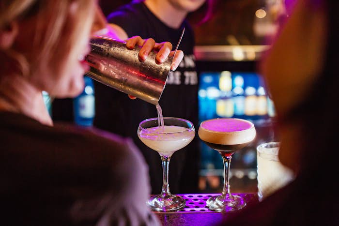 Bar tender pouring an espresso martini for two customers