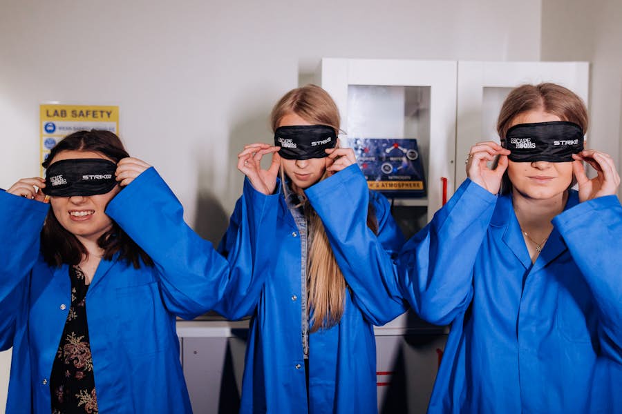 Three girls with blind folds on, in escape room
