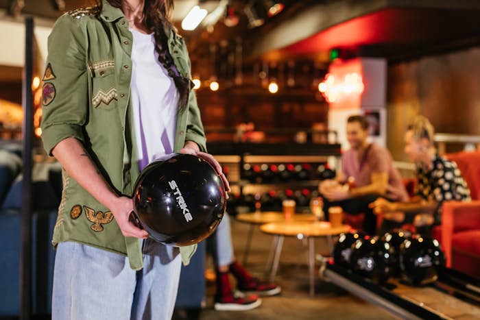 Woman holding a Strike bowling ball preparing to go to the alley