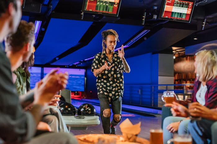Man giving finger guns to group after bowling