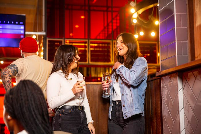 Two women drinking wine and laughing at Strike Bowling