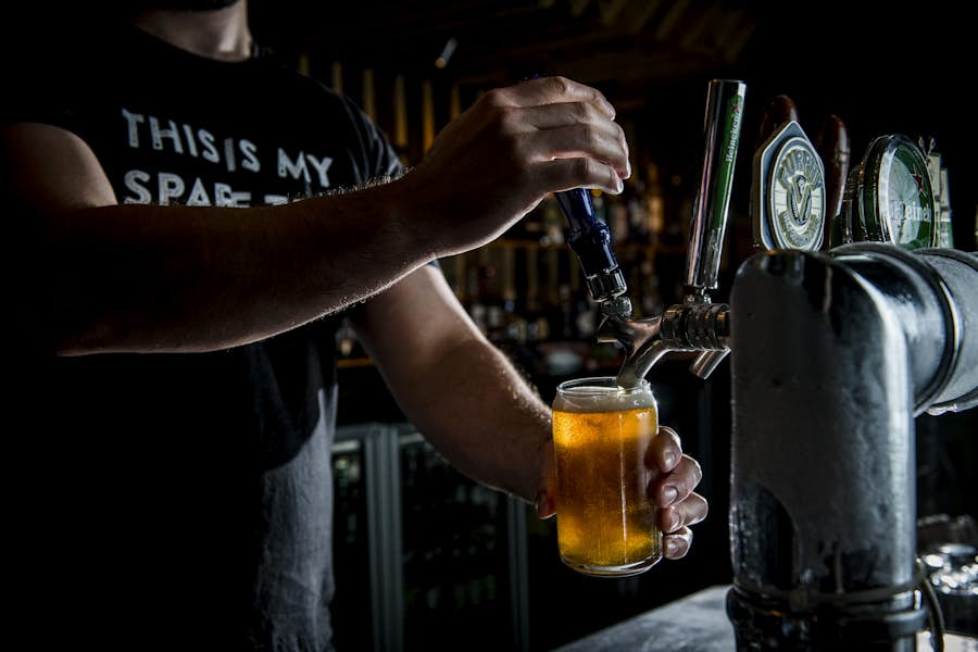 Bar tender pouring cold beer from tap