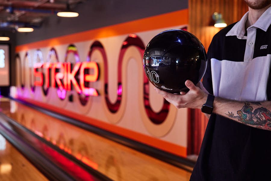 man holding bolding ball beside a bowling lane