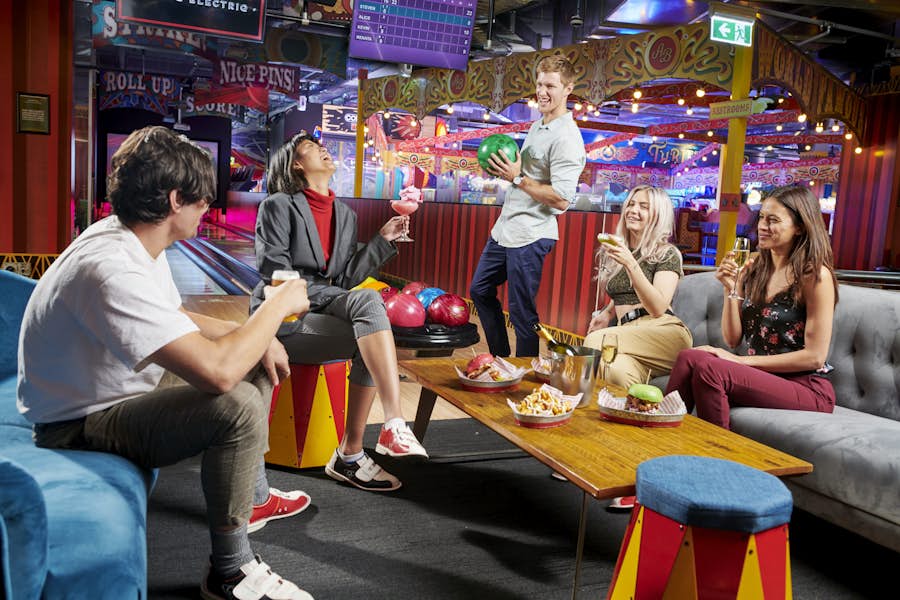 Group of adults chatting in the bowling alley seating area