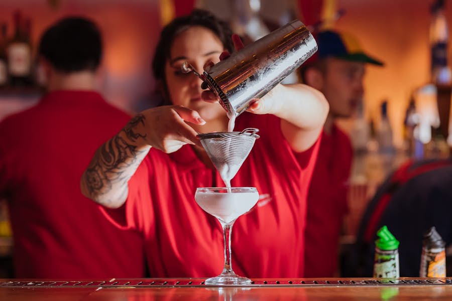 Bartender pouring a cocktail into a glass