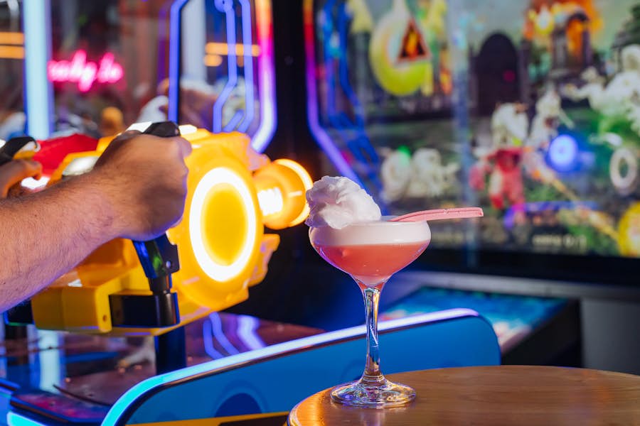 The Circus Sour cocktail sitting on table next to an arcade machine