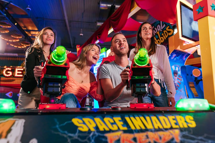 Group of people playing space invaders arcade game