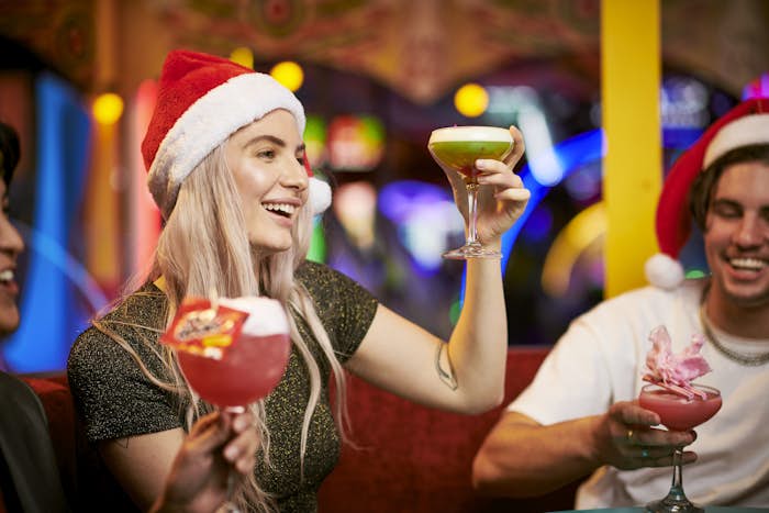 Woman wearing Santa hat raising her martini in a toast