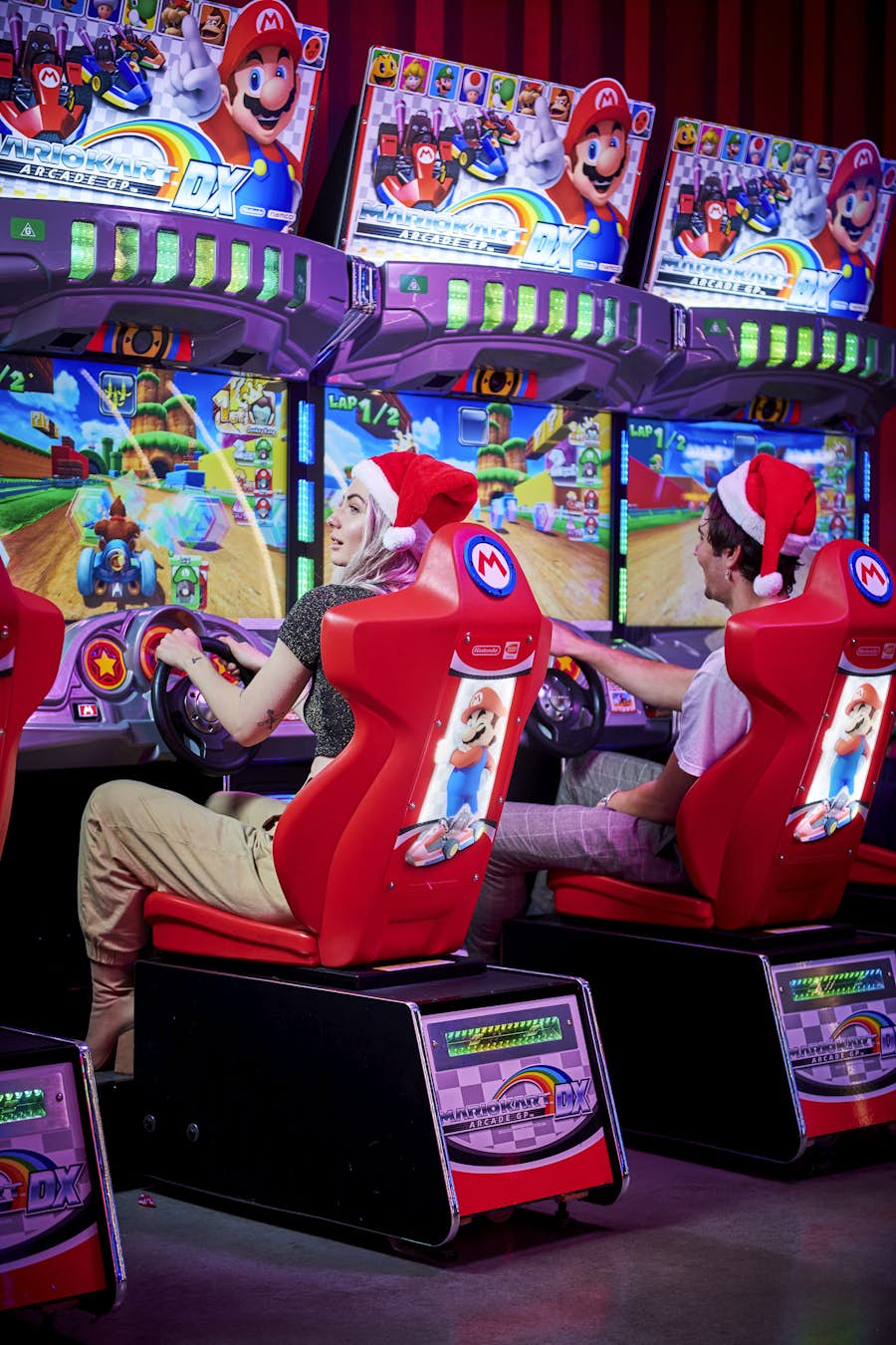 Two people playing Mario Kart in Santa hats