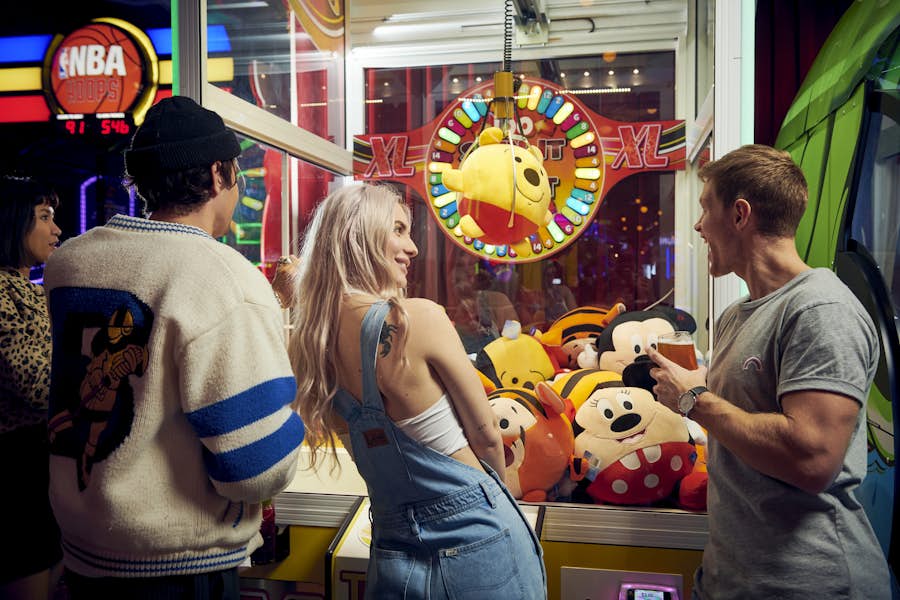 Group of friends gathered around a claw machine