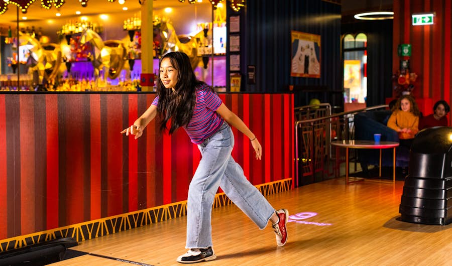 Girl releasing bowling ball onto the lanes