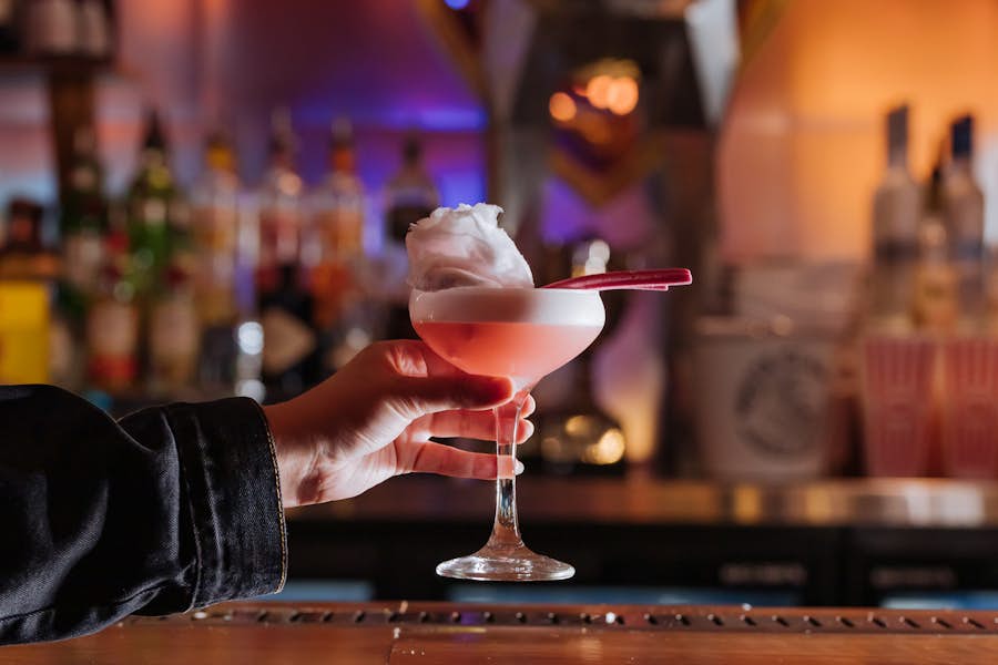 Person collecting their Circus Sour cocktail from the bar