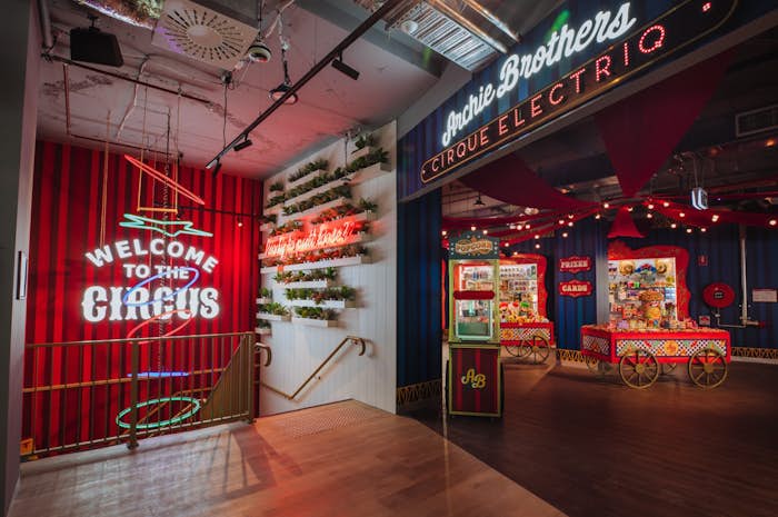 Image of the stairs leading up to the entrance to Archie Brothers Surfers Paradise, there is a neon sign saying "Welcome to the Circus". In the entrance, the redemption store is visible with prizes and lollies on display. .