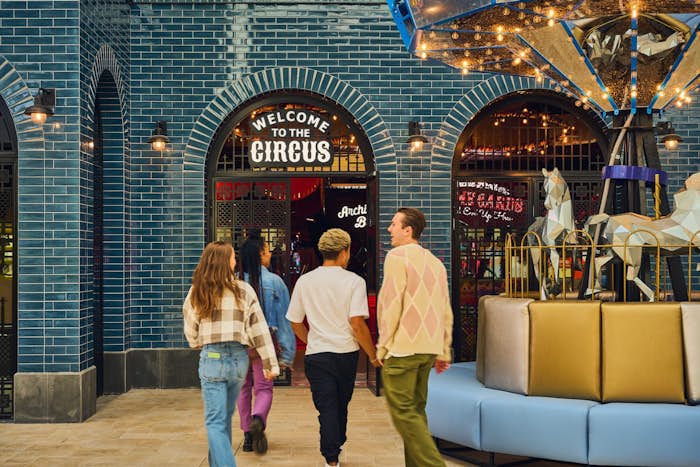Four friends walking towards the entrance at Archie Brothers Chadstone. There is a sign above the door that says "Welcome to the circus"