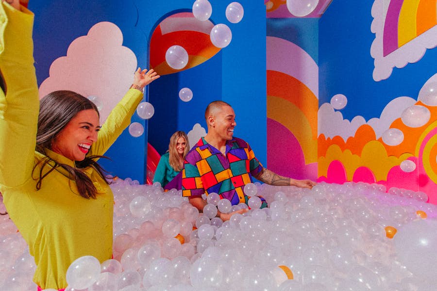 Three friends laughing and playing in giant ball pit