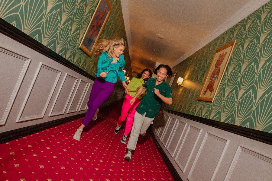 Group of friends running down Hijinz Hotel hallway