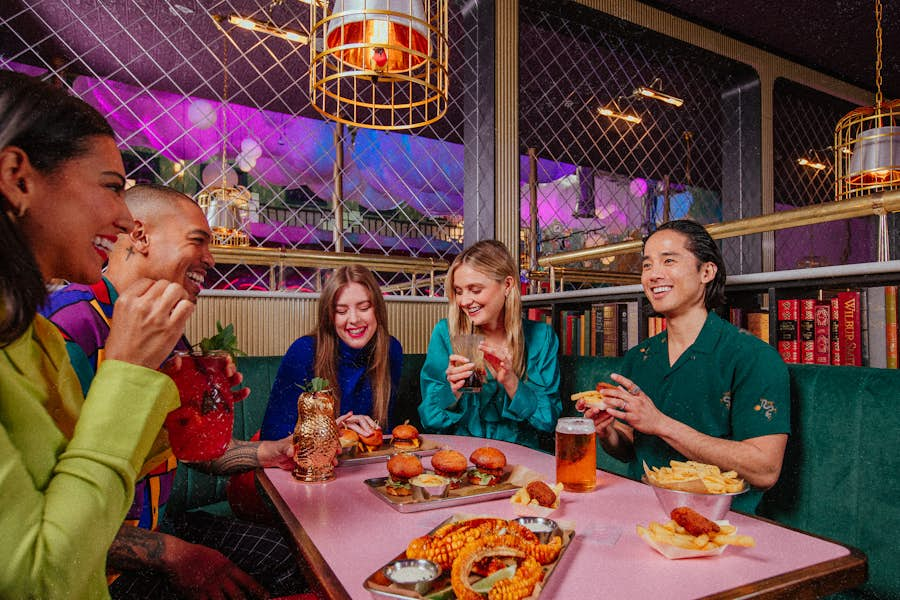 Group pf people sitting in a booth eating and drinking in the Hijinx Hotel bar area