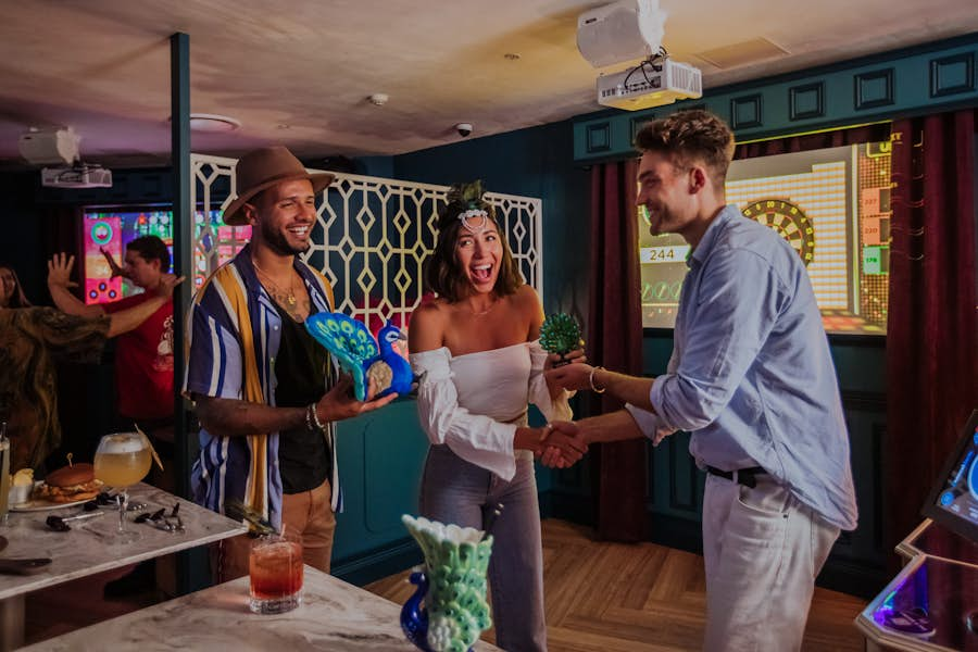 Group cheering and celebrating at La Di Darts holding peacock trophy