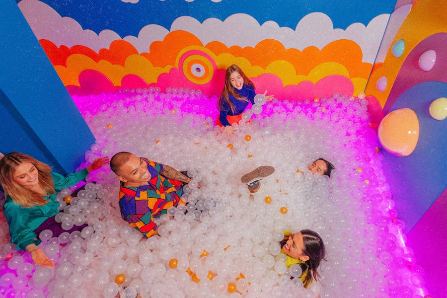 five friends playing and lying in the Hijinx Hotel ball pit