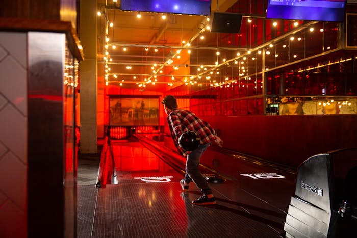 Boy bowling on a bowling lane with fairy lights and red lighting