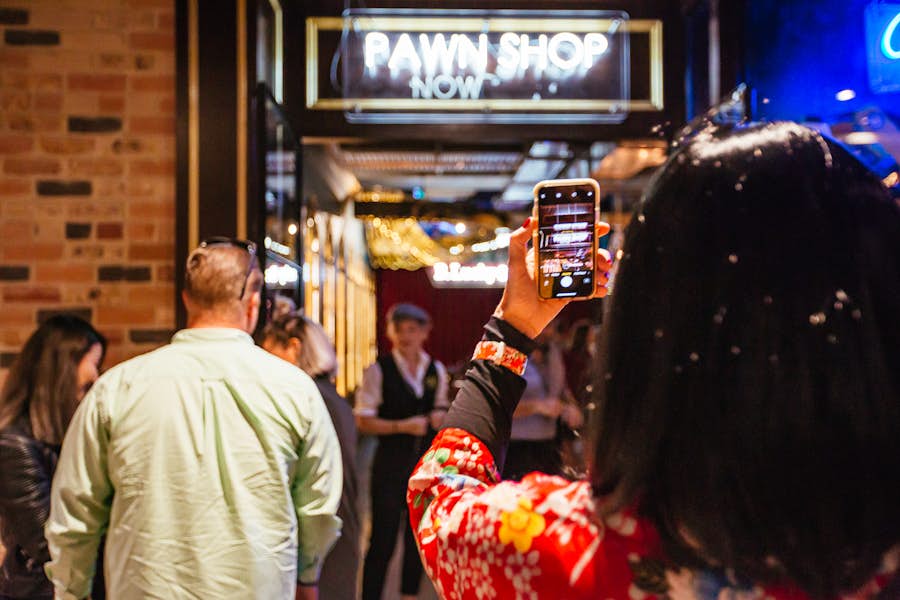 Over the shoulder shot of a woman taking a photo on their phone of the pawn shop