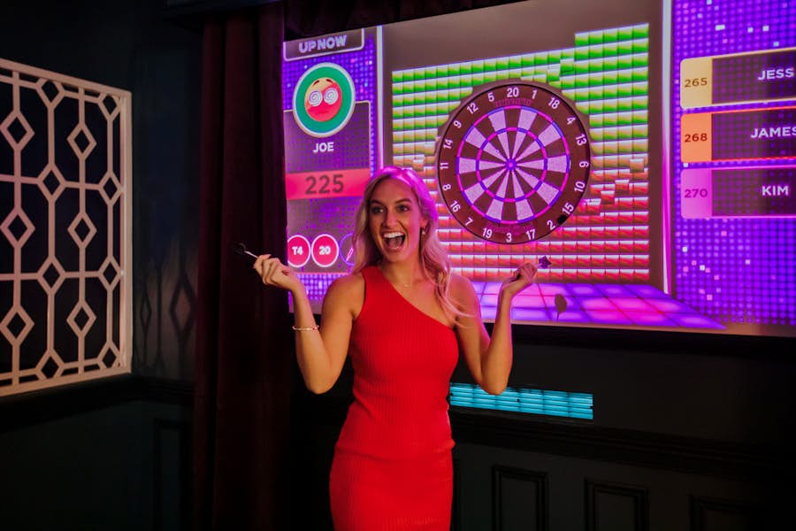 woman in a red dress celebrating at la di darts