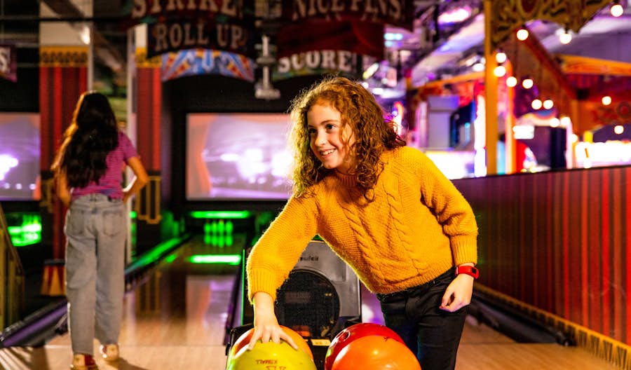 Girl picking up a bowling ball on the lanes