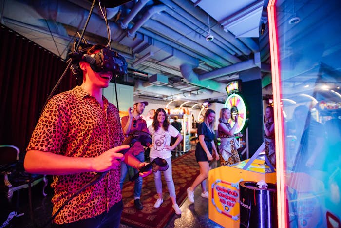 Man wearing a virtual reality headset while playing an arcade game