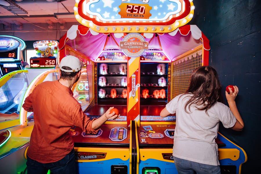 A man and woman playing the Down the Clown arcade game