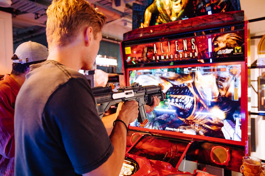 Man playing Aliens Armageddon arcade shooter game