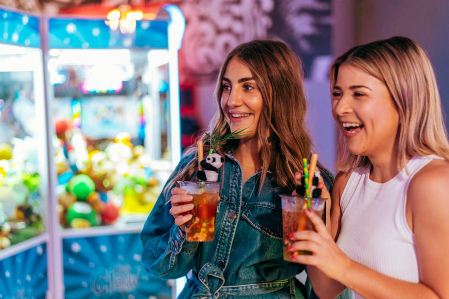 2 women in the arcade drinking cocktails