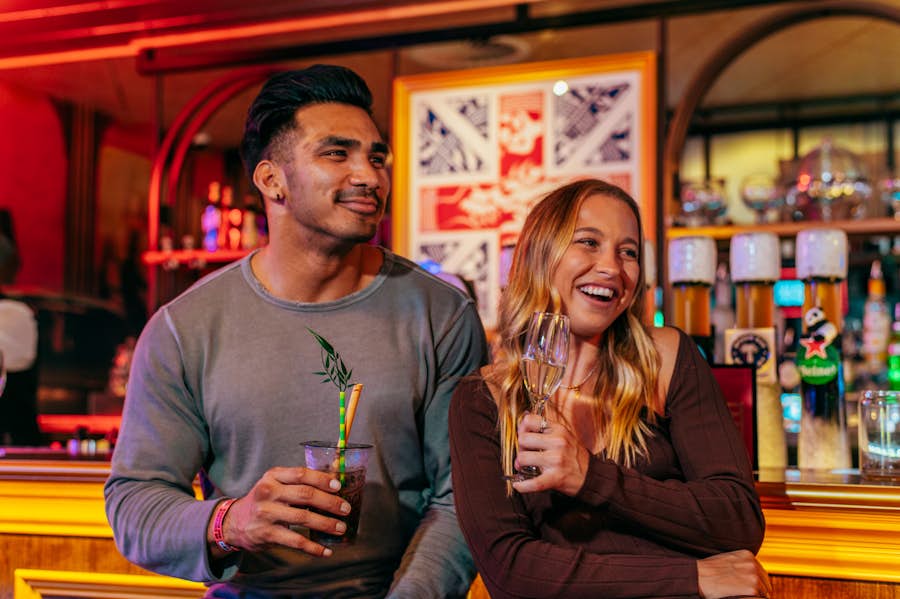 Man and woman standing by the bar drinking cocktails