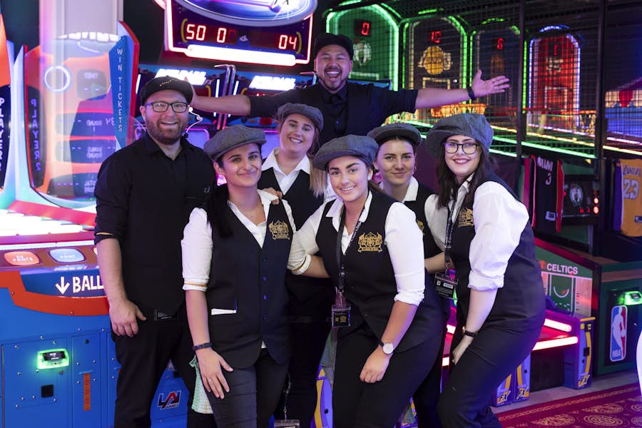 Group of B. Lucky & Sons staff posing in front of an assortment of arcade games