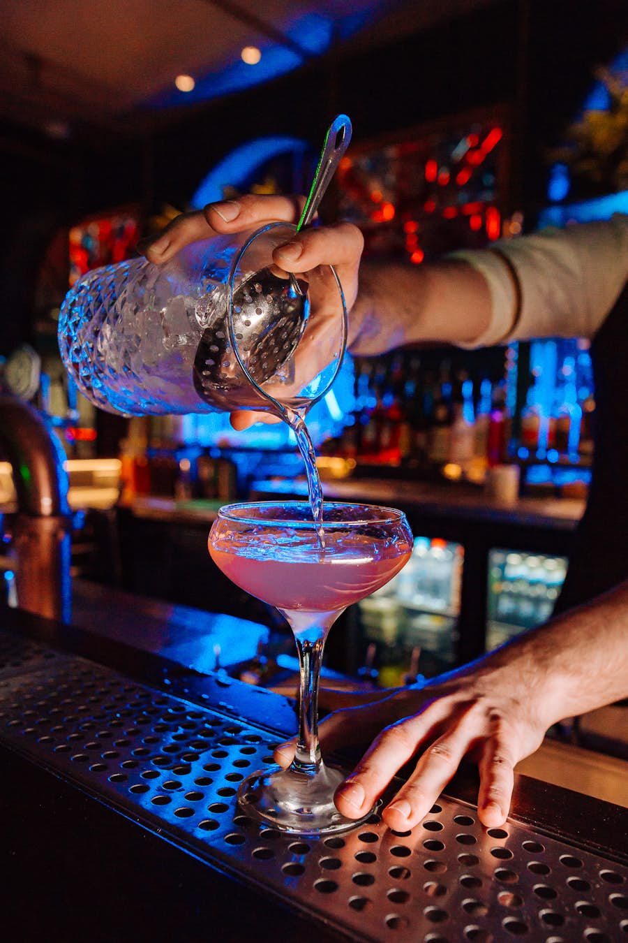 Bar tender pouring a pink cocktail
