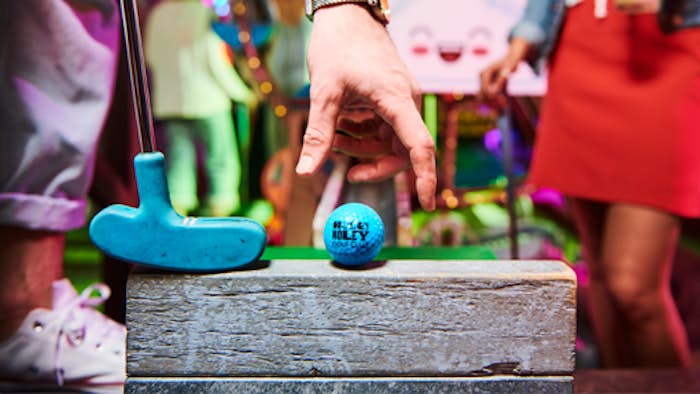 Blue Holey Moley Ball being placed on piece of wood with blue Holey Moley putter in shot
