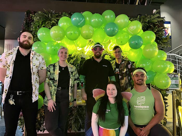 Group of Funlab employees standing in front of green balloon garland