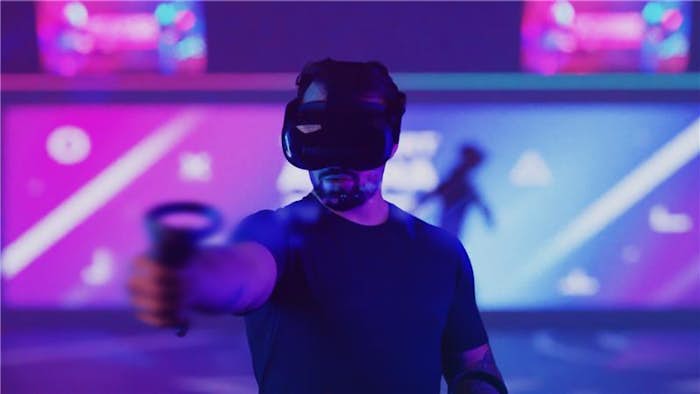 man in purple light room with VR headset on, pointing phaser gun