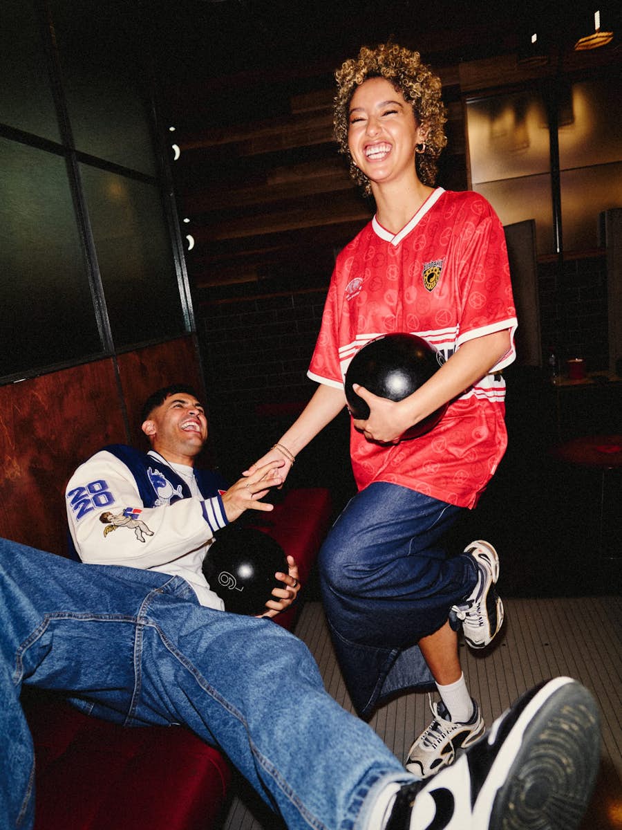 guy lying on lane with a bowling ball and holding hands with a girl holding a bowling ball