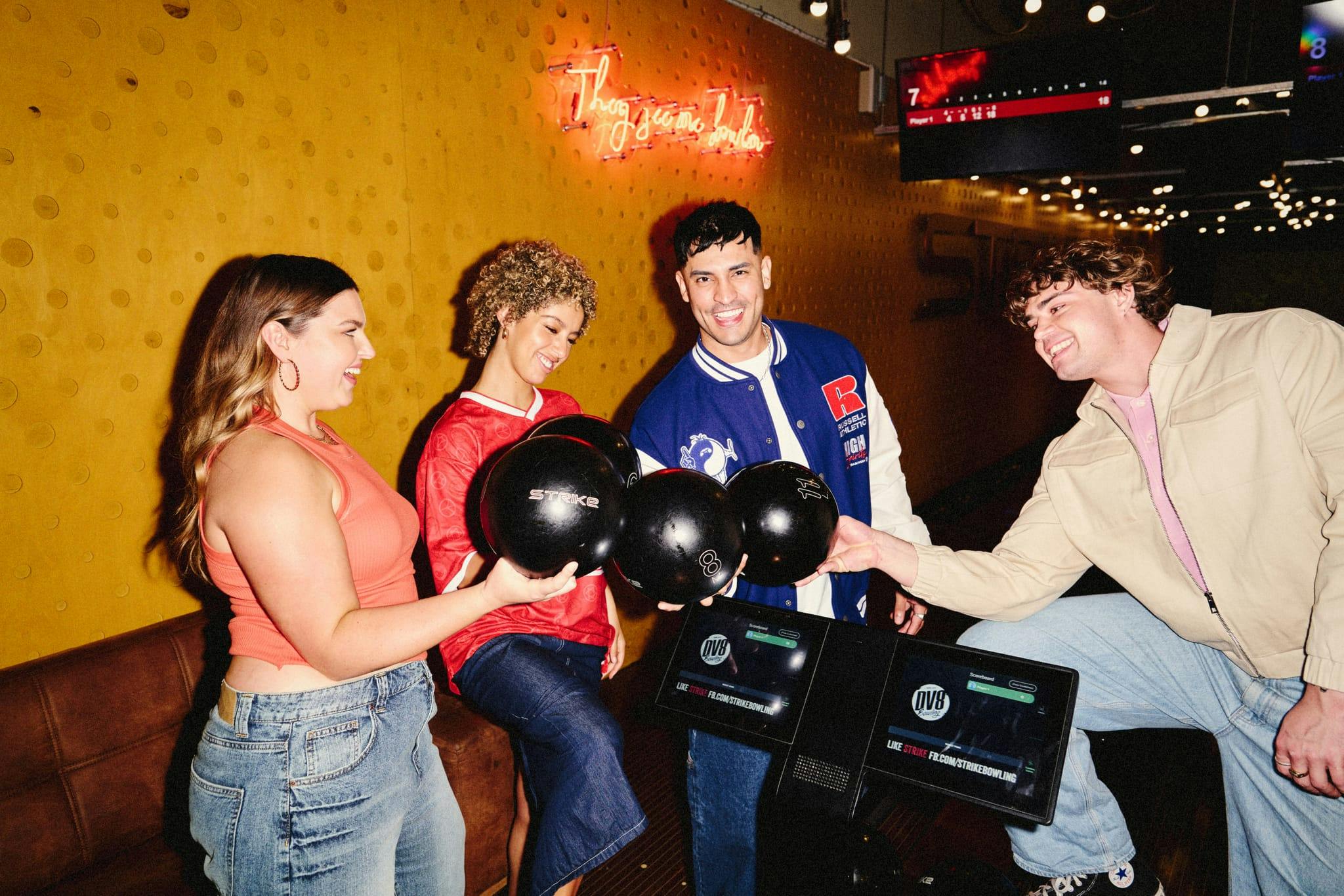 group of friends in a circle each holding a bowling ball and smiling