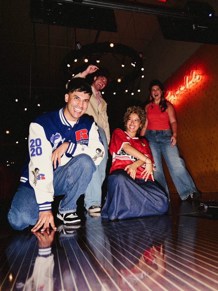 group of 4 friends smiling and celebrating at the start of a bowling lane