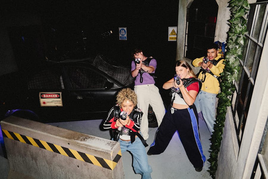 group of friends with laser blasters point at the camera