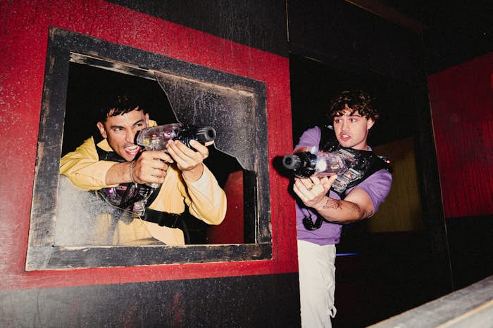 two men hiding behind obstacles with their laser tag equipment