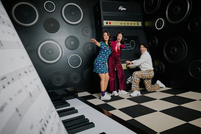 Players in the Hijinx Hotel, black and white Piano room where there is a large floor piano and interactive buttons also along the wall