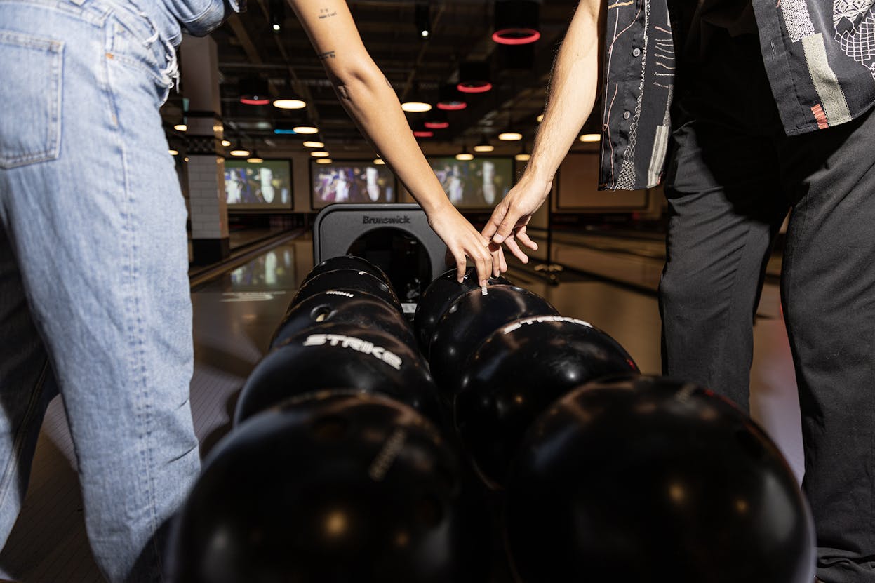 Two people holding hands over bowling balls at Strike