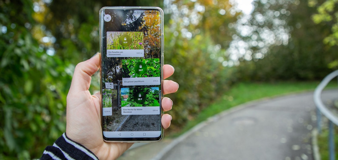 Naturpade-App im Einsatz Eine Hand hält ein Smartphone hoch, auf dem die Naturpfade-App geöffnet ist