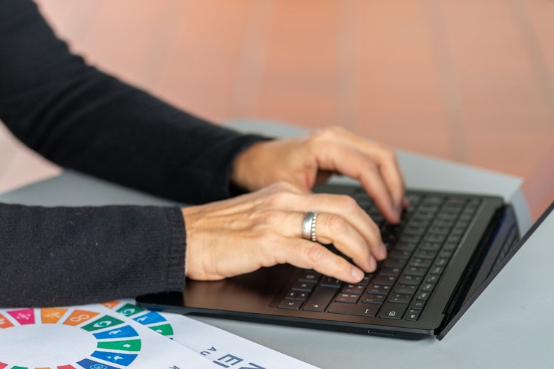 Hände, die auf einer Laptop-Tastatur etwas notieren.