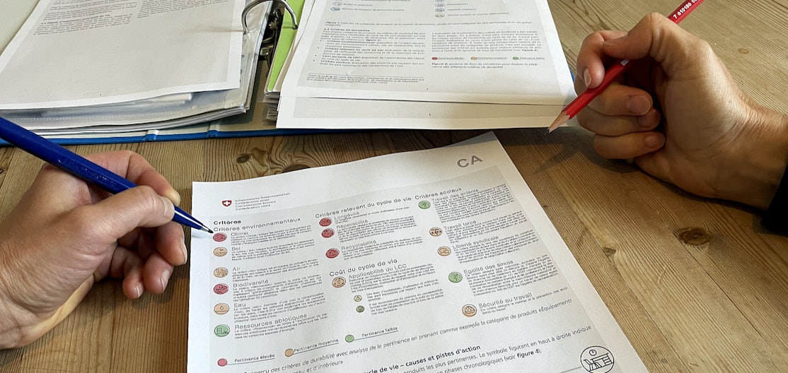 Les critères d’achats publics responsables Un document de la confédération expliquant les critères d’achats publics responsables. Une main tient un crayon, prête à prendre des notes.