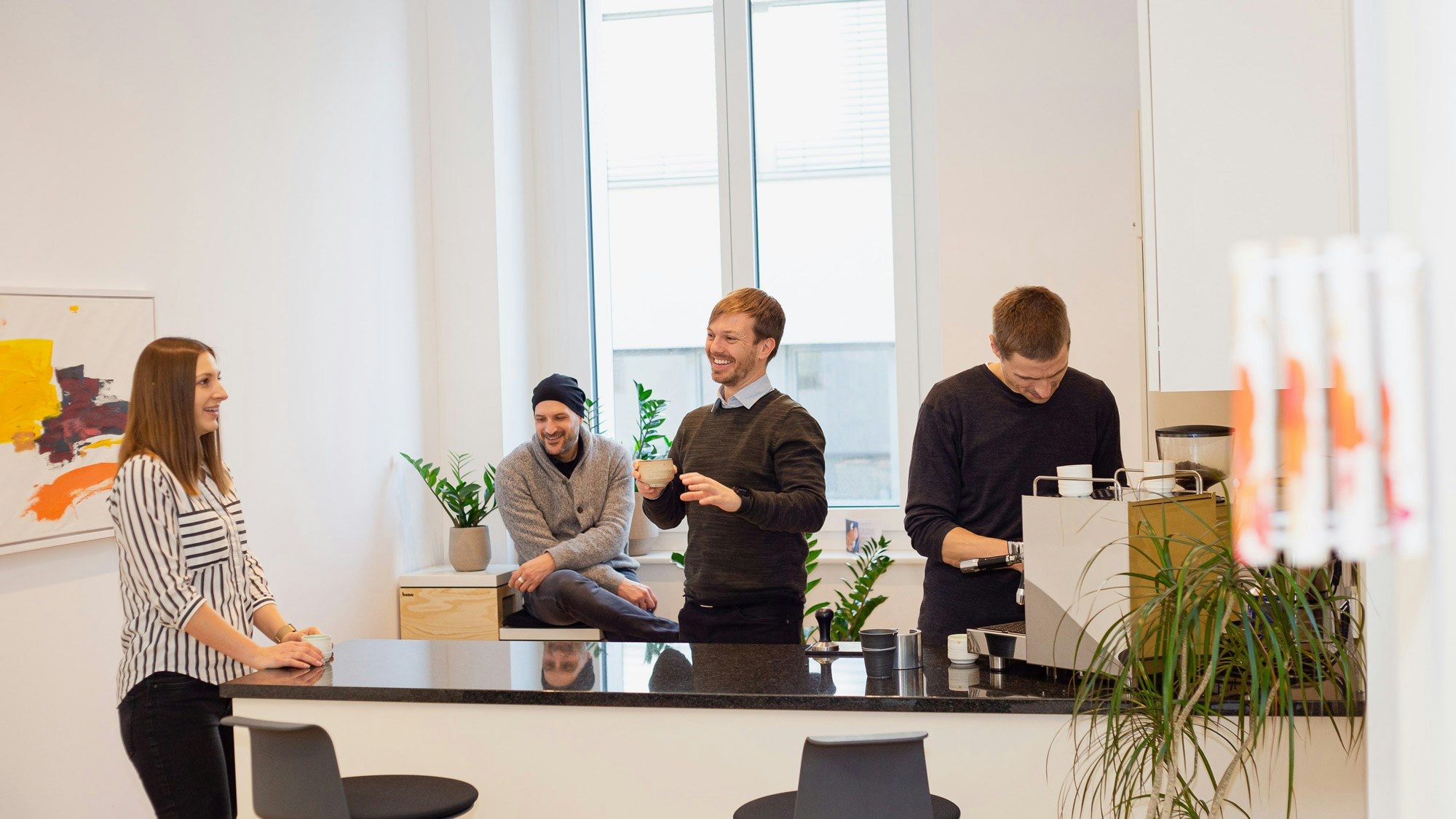 Vier junge Leute in einem hellen Büro in einer freundlichen Atmosphäre.