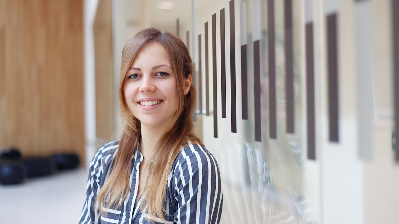 Johanna, smiling, in a blue and white striped shirt against a blurred background.